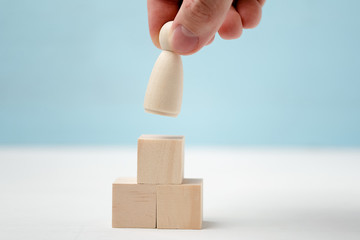 Hand puts or removes wooden figure on toy blocks are located as podium.