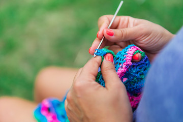 Craftswoman's hands knitting shawl with crochet - obrazy, fototapety, plakaty