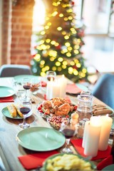 Setting of christmas table on festive holidays, full of traditional food with turky and delicious meals around the tree lights and decoration