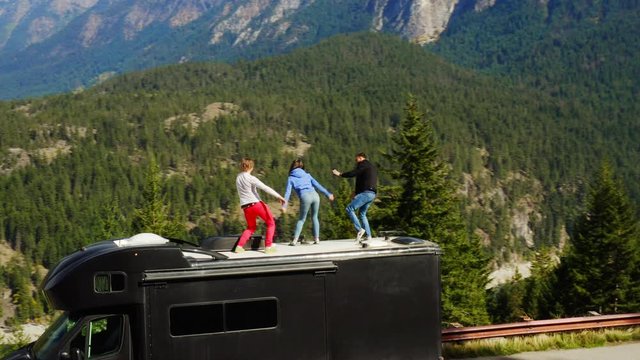 Tourists dancing on roof of RV. Winner dance. Celebrating, travel around USA on RV, aerial of endless forest and mountains