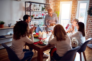 Family and friends dining at home celebrating christmas eve with traditional food and decoration, showing proud turkey cooking