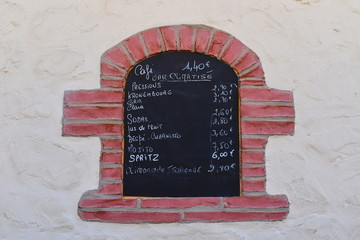 Oven shaped coffee bar menu on a wall in south of France. Alcoholic and non-alcoholic drinks price list on a back board written in chalk. 