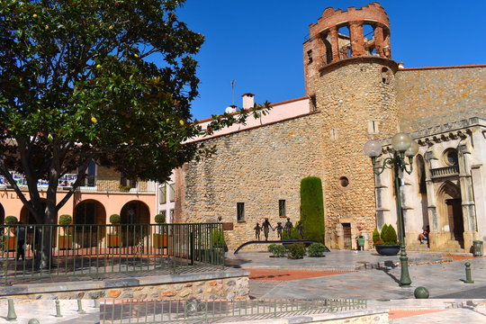 Main square in a charming medieval town in south of France. Stone wall, tower, arches and fruit tree at the background. Sunny summer day in Europe.
