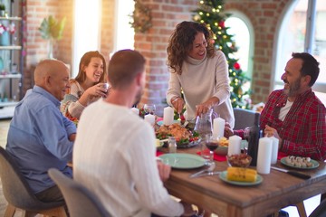 Beautiful family smiling happy and confident. Carving roasted turkey celebrating Christmas at home