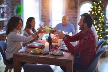 Beautiful family smiling happy and confident. Eating roasted turkey celebrating Christmas at home