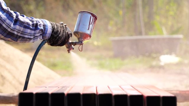 Construction worker spraying paint to steel pipe to prevent the rust on the surface