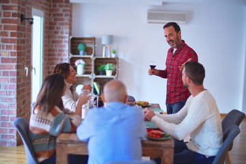 Beautiful family smiling happy and confident. Man speaking speech with cup of wine on hand celebrating Thanksgiving Day at home