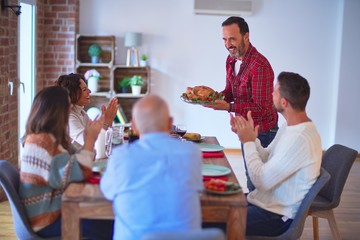 Beautiful family smiling happy and confident. Showing roasted turkey and applauding celebrating Thanksgiving Day at home