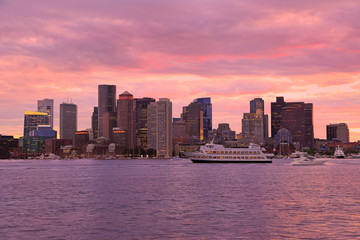 Boston skyline at sunset wit cruise boat sailing on the foreground, USA