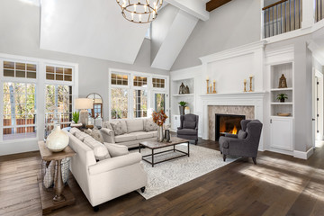 Beautiful living room in new traditional style luxury home. Features vaulted ceilings, fireplace with roaring fire, and elegant furnishings. - Powered by Adobe