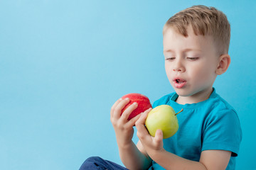 Fototapeta na wymiar Little Boy Holding an Apples in his hands on blue background, diet and exercise for good health concept