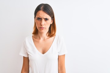 Fototapeta premium Beautiful redhead woman wearing casual white t-shirt over isolated background skeptic and nervous, frowning upset because of problem. Negative person.