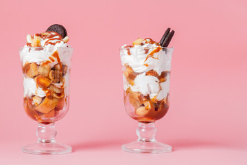 Sweet dessert in glass with biscuit and whipped cream on pink bsckground, selective focus and blank space