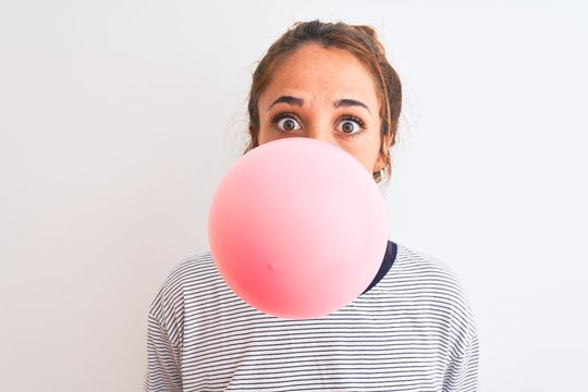 Young Redhead Woman Chewing Gum And Blowing Hair Bubble Over White Isolated Background Scared In Shock With A Surprise Face, Afraid And Excited With Fear Expression