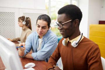 Portrait of two college students using computers for research project in library, copy space