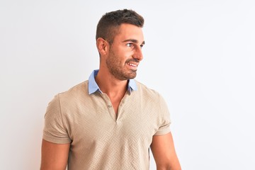 Fototapeta premium Young handsome man wearing elegant t-shirt over isolated background looking away to side with smile on face, natural expression. Laughing confident.