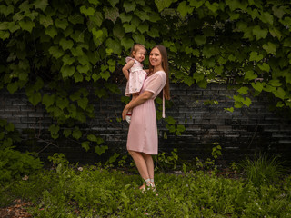 Mom and daughter walk and play in the park. Dressed in dresses. Sunny day, weekend in a city park.