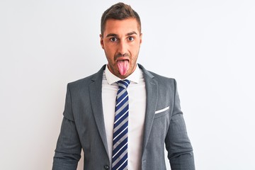 Young handsome business man wearing suit and tie over isolated background sticking tongue out happy with funny expression. Emotion concept.