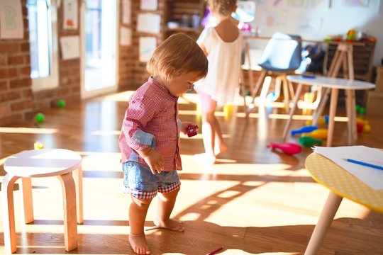 Beautiful toddlers smiling happy playing around lots of toys at kindergarten