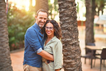 Middle age beautiful couple smiling happy and confident at town park. Standing with smile on face and hugging