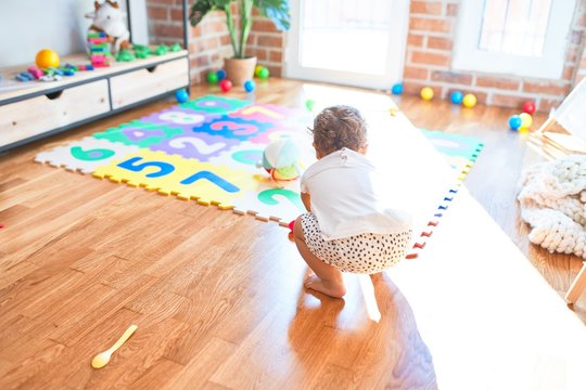 Adorable toddler playing around lots of toys at kindergarten