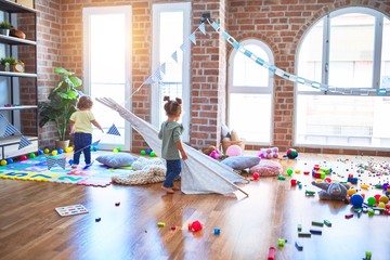 Adorable toddlers playing with tipi around lots of toys at kindergarten © Krakenimages.com