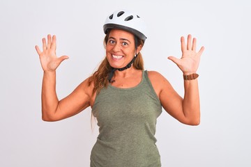 Obraz na płótnie Canvas Middle age mature cyclist woman wearing safety helmet over isolated background showing and pointing up with fingers number ten while smiling confident and happy.