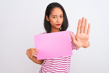 Young beautiful chinese woman holding banner standing over isolated white background with open hand doing stop sign with serious and confident expression, defense gesture