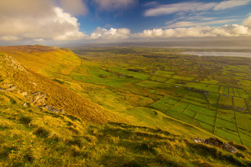Fototapeta premium Beautifull weather in Irish mountains and green grass. View from top of the Ben Bulben moutain in Sligo, Ireland. Dramatic sky during summer sunset.
