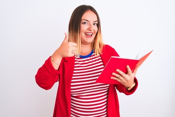 Young beautiful woman reading book standing over isolated white background happy with big smile doing ok sign, thumb up with fingers, excellent sign