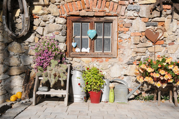 Fototapeta na wymiar Alter Bauernhof mit dekorativem Fenster in Steinwand