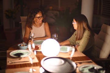 Beautiful mother and daughter on dinner smiling at terrace