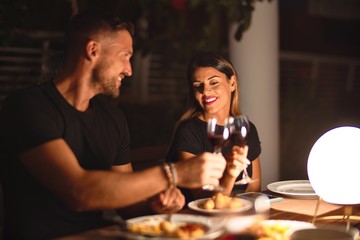 Young beautiful couple dinning on celebration toasting and smiling at terrace