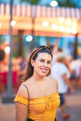 Young beautiful girl smiling happy and confident walking at the town street, standing with a smile on face around night lights bokeh