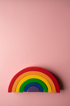 Bright wooden rainbow toy  on a pink background with copy space - creative toy concept flat lay portrait