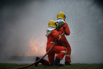 2 firefighters spraying water in fire fighting operation, Fire and rescue training school regularly to get ready