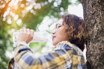 Girl drinking water from bottle in forrest