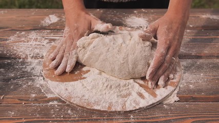 Female hands in flour closeup kneading dough on table