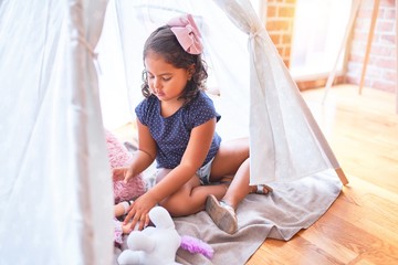 Beautiful toddler girl sitting on the floor playing with unicorn and doll inside  tipi at kindergarten © Krakenimages.com