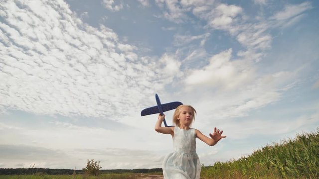 A little girl runs and launches a paralon toy airplane.