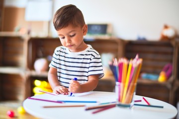 Beautiful toddler boy drawing cute draw using colored pencils at kindergarten © Krakenimages.com