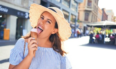 Young beautiful woman eating ice cream cone walking down the street of Tenerife on a sunny day of summer on holidays
