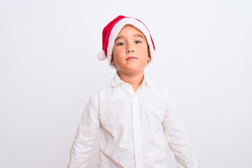 Beautiful kid boy wearing Christmas Santa hat standing over isolated white background Relaxed with serious expression on face. Simple and natural looking at the camera.