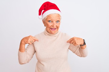 Senior grey-haired woman wearing Crhistmas Santa hat over isolated white background looking confident with smile on face, pointing oneself with fingers proud and happy.