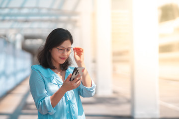Fototapeta premium Young woman using smartphone under harsh sun light