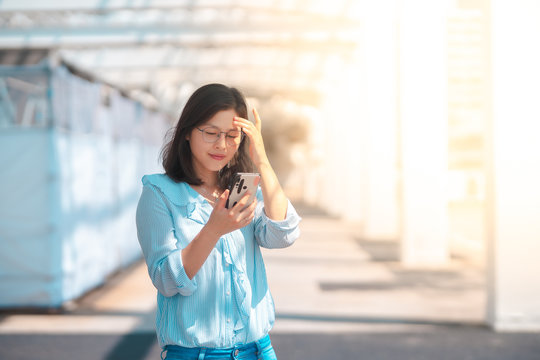 Young woman using smartphone under   harsh sun light