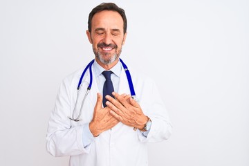 Middle age doctor man wearing coat and stethoscope standing over isolated white background smiling with hands on chest with closed eyes and grateful gesture on face. Health concept.