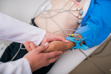 Doctor ( cardiologist ) is attaching vacuum sensors to an elder ( senior )patient for recording ECG...