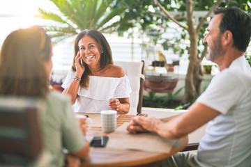 Beautiful family sitting on terrace drinking cup of coffee talking on the smartphone and smiling