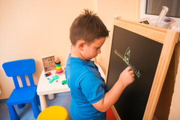 Young kiddo drawing something on the black board in Pediatrician's office.